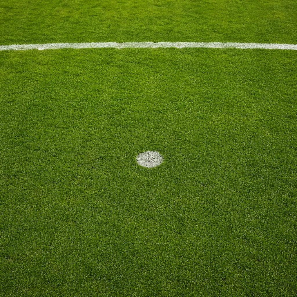 High angle shot of a soccer penalty spot on well-maintained green grass, soft na