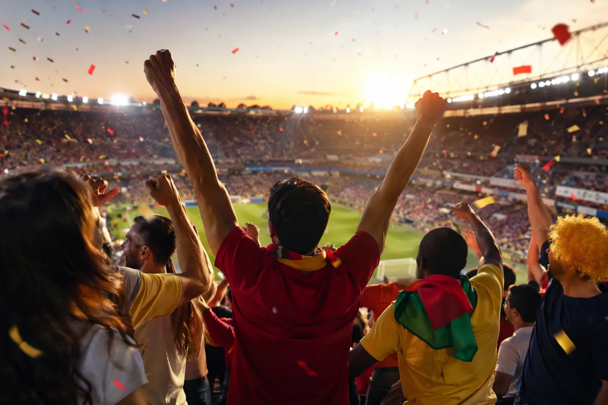 Dynamic football stadium atmosphere at golden hour, colorful confetti floating in air, div