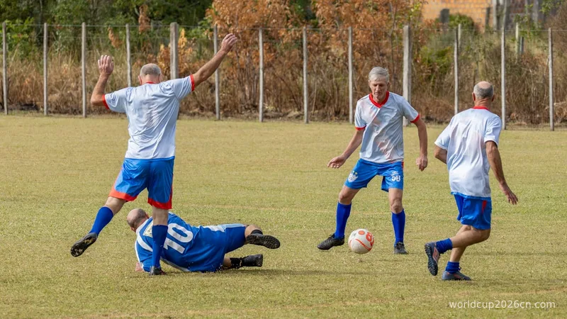 Four men playing soccer, one falling on the field.