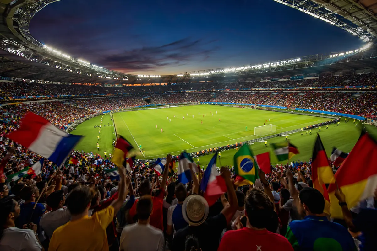 Wide shot of a modern football stadium during a World Cup match, blurred players on the pi