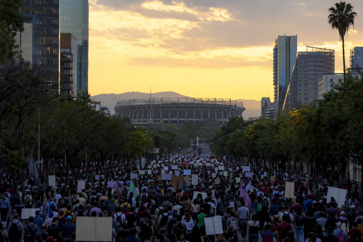 Wide shot of peaceful protest crowd walking on Mexico City main avenue, distant view of mo