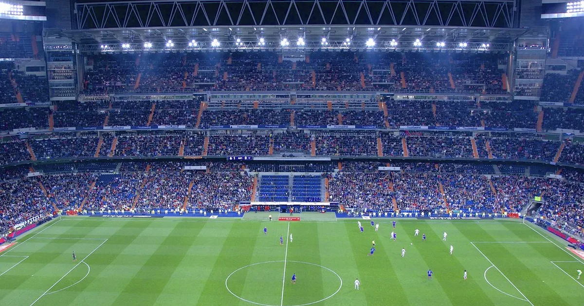 Editorial news photo of a vibrant World Cup football stadium at dusk, filled with cheering